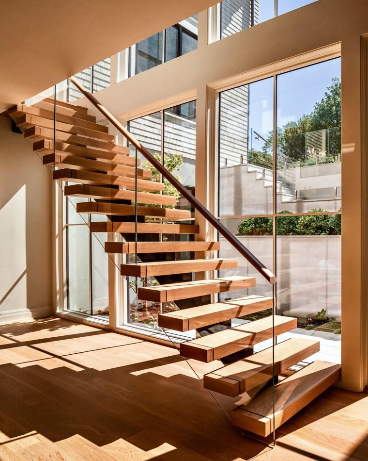 Floating oak stair beside a double-height window wall